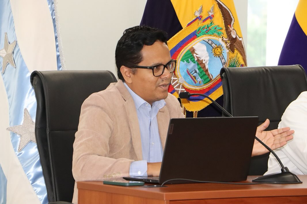 Byrone Tomalá interviniendo ante un micrófono con una computadora